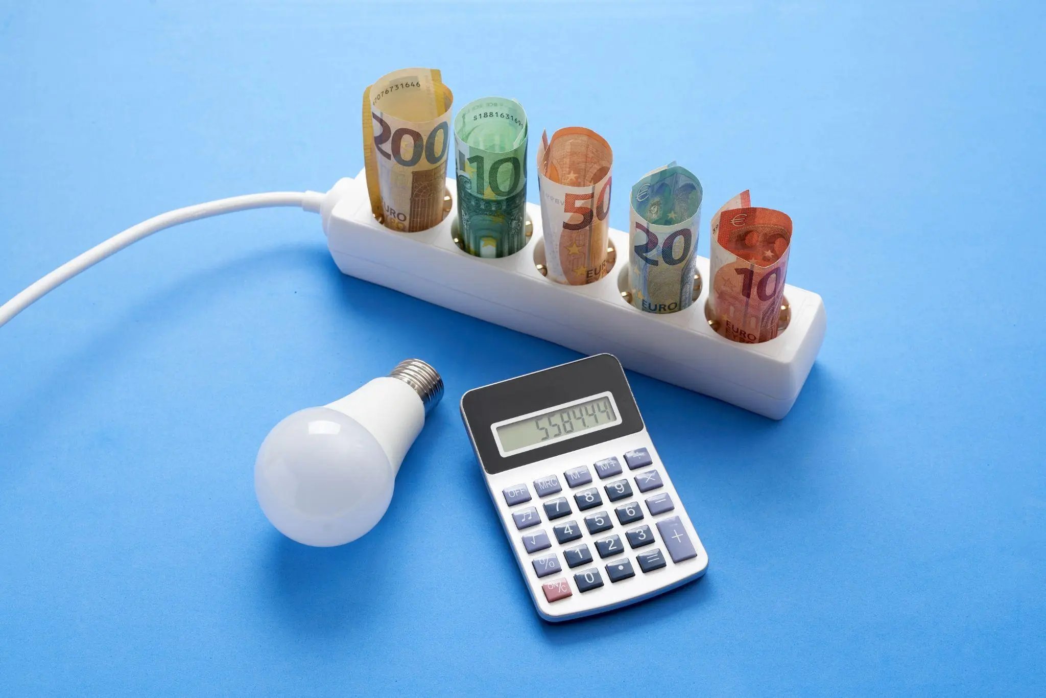 electric power strip with banknotes on blue background with a light bulb and a calculator